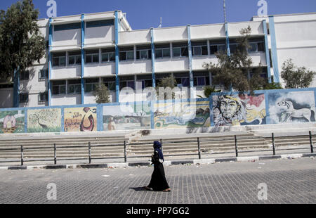 Gaza, Gaza, Palästina. 24 Sep, 2018. Eine palästinensische Frau geht an der geschlossenen Hilfswerk der Vereinten Nationen (UNRWA) zentrale Gebäude während eines Generalstreiks gegen die jüngsten Entscheidungen der Verwaltung der Agentur gegenüber Mitarbeitern in Gaza Stadt. Credit: Mahmoud Issa/SOPA Images/ZUMA Draht/Alamy leben Nachrichten Stockfoto