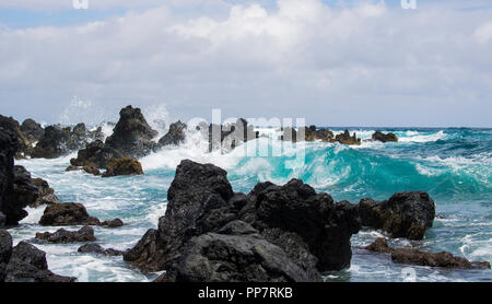 Grobe Lava Küste mit türkisfarbenen Wellen Curling und Brechen durch Felsen Stockfoto