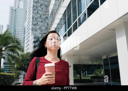 Gerne Chinesisch weiblicher Manager pendeln und Holding Kaffeetasse. Zuversichtlich asiatischen Geschäftsfrau im späten zu Fuß schnell zu Büro morgens. Stockfoto