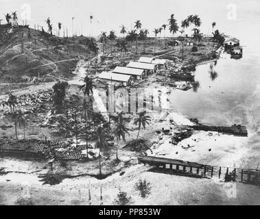 Guadalcanal-Tulagi Anlandungen, 7-9 August 1942. Ruinierte und Flugzeuge im Japanischen Seaplane Base auf Tanambogo Insel östlich von Tulagi. Foto ist vom 8. August 1942 und war wahrscheinlich zu kurz vor US-Marines die Insel gefangen. In dieser Ansicht sieht über Westen, mit einem verbrannten Pier im Vordergrund, Kraftstoff Fässer gestapelt auf der linken und das Wrack eines Wasserflugzeugs unter den Bäumen in der Mitte. Die Gebäude sind wahrscheinlich im Laufe von Tagen der Insel als Royal Australian Air Force ausgehändigt. Stockfoto