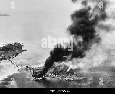 Guadalcanal-Tulagi Anlandungen, 7-9 August 1942 - Brände unter den japanischen Einrichtungen und Wasserflugzeuge auf Tanambogo Insel östlich von Tulagi, am ersten Tag der Invasion, 7. August 1942. In dieser Ansicht sieht über SSW, mit Gavutu Insel auf der linken Seite, Anschluss an Tanambogo durch einen Damm. Stockfoto