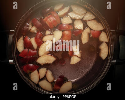 Bunte Apfelscheiben, Obst Mix in einem Topf. Erfrischende Frucht Apfelwein Punsch Party Trinken. Organische Nahrung Warm Glow Hintergrund. Stockfoto