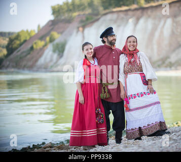 Ein Mann und zwei Frauen in Russischen Trachten posieren für die Kamera auf dem Hintergrund einer wunderbaren Landschaft Stockfoto