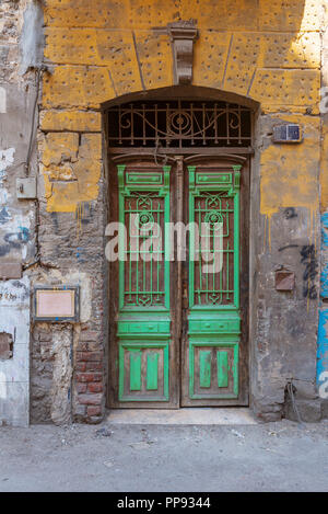 Alten grunge Grün gestaltet lackiert Tür auf schmutzig gelb lackiert Steinmauer, alte Kairo, Ägypten Stockfoto