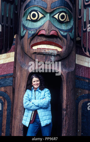 Schöne junge Frau lächelnd an einen Totempfahl, Alaska, 1981, USA Stockfoto