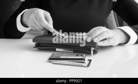 Schwarze und weiße Nahaufnahme Bild der Unternehmerin setzen Kreditkarten in Wallet Stockfoto