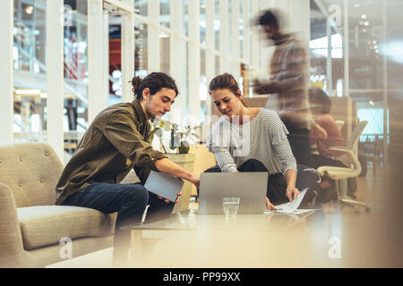 Geschäftsfrau, Ideen zu teilen, die mit einem Client im Amt. Mitarbeiter in diesem Notebook und Arbeiten im Büro. Stockfoto