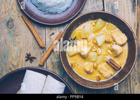 Thai Massaman Curry (Chicken Curry) mit Zimtstangen und Flugzeug riсe auf Holz- Hintergrund. Kokosmilch Curry. Stockfoto