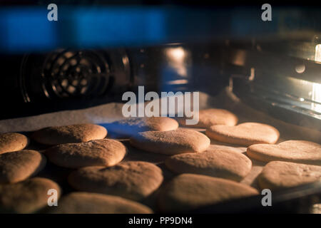 Weihnachtsplätzchen backen im Ofen. Weihnachten backen. Lebkuchen Kekse auf backblech. Stockfoto