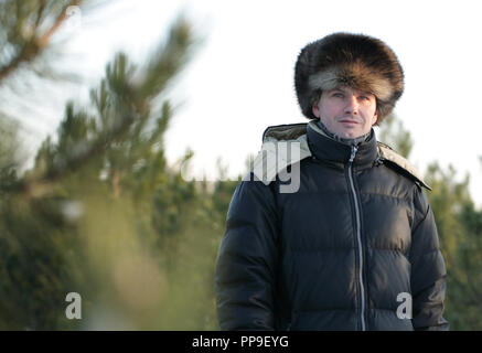 Russischer Mann in Winterkleidung und russischer Pelzhut Ein Pinienwald Stockfoto