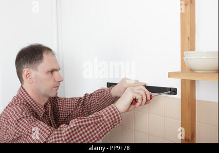 Mann Installation des magnetischen Messer Rack auf einem Küche Wand Stockfoto