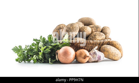 Dreckige Kartoffeln in Holz Korb aus sellerieblätter Zwiebel und Knoblauch auf weißem Hintergrund Reif. Stockfoto