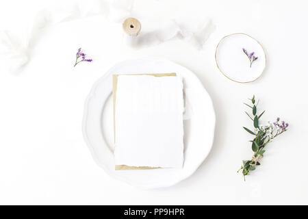 Festliche Hochzeit, Geburtstag Tisch mit Porzellan Teller, Seidenbändern und floralen Bouquet aus Eukalyptus, limonium Blumen. Eine leere Karte mockup. Im rustikalen Restaurant Menü Konzept. Flach, Ansicht von oben Stockfoto