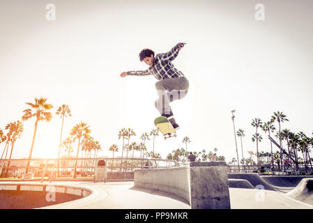 Cooler Skateboarder im Freien - Afroamerican Kerl springt mit seinem Skate und Durchführen einer Trick Stockfoto