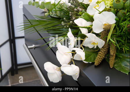 Ein Blumengebinde auf dem Sarg in einer Leichenhalle Stockfoto