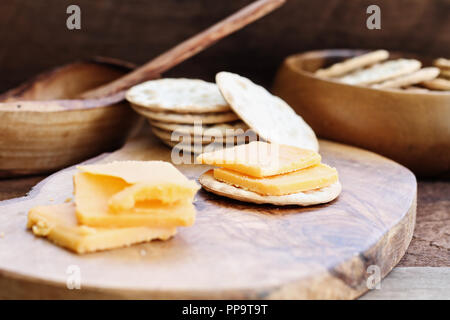 Cheddar Käse und Cracker Vorspeise über eine rustikale Hintergrund. Stockfoto