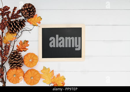 Rustikale Fallen der Blätter im Herbst, Tannenzapfen und mini Kürbisse mit schiefertafel Für kostenlose Kopie Platz für Text über eine rustikale Hintergrund. Bild sho Stockfoto