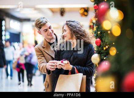 Ein junger Mann, der ein Geschenk für seine Freundin im Einkaufszentrum zu Weihnachten. Stockfoto