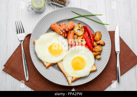 Set für Frühstück Spiegeleier, gegrilltes Gemüse, Wurst. Brot auf einem Holztisch. Stockfoto