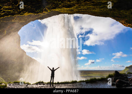 Gerne Frau Gefühl die Macht der Wasserfall Seljalandsfoss im Süden von Island, Person hinter dem Bach und berühmten isländischen landm Stockfoto