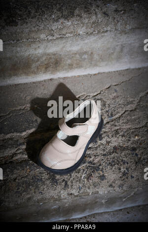 Baby Schuh liegen auf alten Betonboden aufgegeben. Verlorene Schuhe für Kinder. Stockfoto