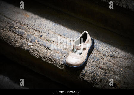 Baby Schuh liegen auf alten Betonboden aufgegeben. Verlorene Schuhe für Kinder. Stockfoto