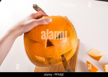 Carving orange Kürbis für Halloween Urlaub. Mädchen Hand mit Messer schneidet und Jack o Laternen vorbereiten. Close Up, selektiver Fokus Stockfoto