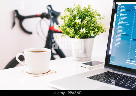 Home Office mit Caffe und Notebook auf weißen Tisch mit Road Bike im Hintergrund Stockfoto