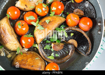 Pilze und Tomaten, in einer flachen Pfanne gebraten Rühren, Pan, mit frisch gehackter Petersilie garniert Stockfoto