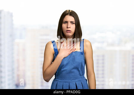 Schöne brünette Frau mit Husten. Hübsches Mädchen Husten und die Hand auf die Brust. Virale Infektion Symptome. Stockfoto