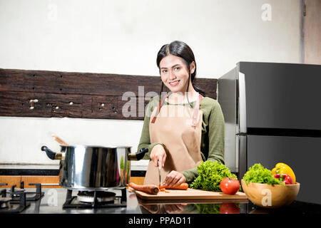 Lächelnd asiatische Frau schneidet das Gemüse in der Küche Stockfoto