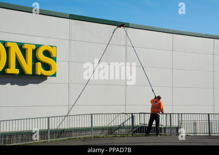 Arbeiter mit langen Pol-Abzieher, der das Äußere einer Supermarktwand reinigt, Westgate, Aldershot, UK Stockfoto
