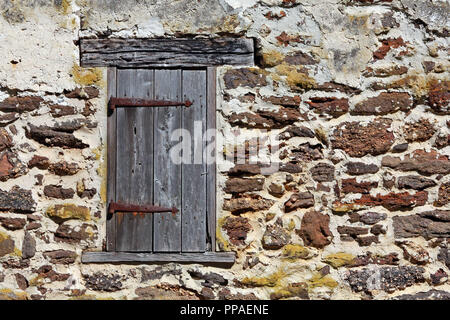 Alte hölzerne Fensterläden mit rostigen Scharniere auf Eisen Gebäude aus Stein Wand Stockfoto