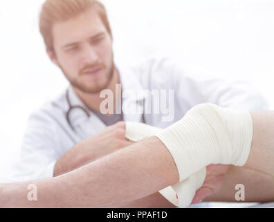 Arzt bandagieren eine Wunde am Bein des Patienten Stockfoto