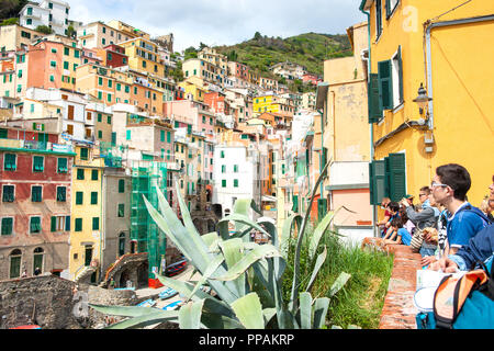 RIOMAGGIORE ITALIEN - 26. APRIL 2011; junge Reisende auf der Suche von einem Tal sie zu anderen mit Reihen von Fenstern und Fensterläden der Ferienwohnungen aufgebaut Seite o Stockfoto