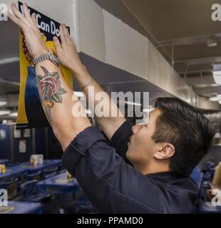 Ozean (Aug. 29, 2018) Mass Communication Specialist 3. Klasse Allen Lee haengt ein Plakat für die Gleichstellung der Frauen in der aft Chaos Decks auf der Nimitz-Klasse Flugzeugträger USS Abraham Lincoln (CVN 72). Abraham Lincoln ist unterwegs mit Carrier Strike Group 12 (CSG 12) Durchführung von Funktionsprüfung-1 (OT-1) für die F-35C Lightning II Joint Strike Fighter. Stockfoto