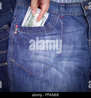 Menschliche Hand klebt diese Tasche auf der Vorderseite der blauen Jeans Papiergeld Dollar, in der Nähe Stockfoto