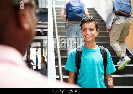 Männliche Schüler im Gespräch mit Lehrer in langen Korridor Stockfoto