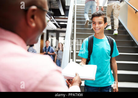 Männliche Schüler Übergabe Projekt Lehrer in langen Korridor zu Stockfoto