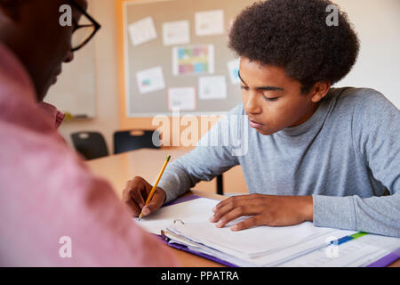 High School Tutor Die männlichen Kursteilnehmer Einzelunterricht am Schreibtisch Stockfoto