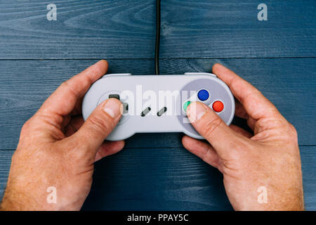 Mann spielt Retro video spiel mit Controller auf dunklem Hintergrund Stockfoto