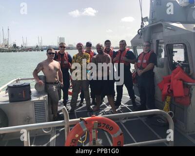 Drei Männer stehen mit ihrem Retter nach aus Ihren sinkenden Schiffes, auf einer Station Galveston 45-Fuß-Antwort Boot - Medium Crew in der Nähe von Galveston, Texas Jan. 13, 2018 übertragen werden. Alle drei Männer waren Rettungswesten von der Küstenwache vor ihrer Rettung. Stockfoto