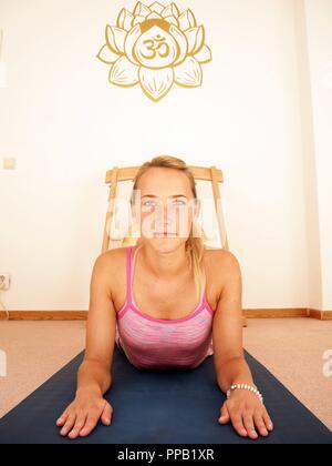 Junge hübsche Frau ist Yoga in ihrem rosa sport Anzug mit einem Feng Gong im Hintergrund. Stockfoto