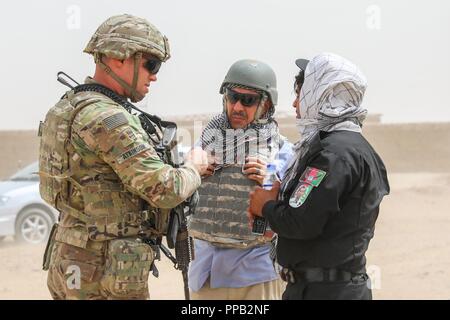 Der PROVINZ KANDAHAR, Afghanistan (14 August 2018) - - US-Armee 2. Lt. Donald Atkinson, Zugführer für 2 Infantry Brigade Combat Team, 4 Infanterie Division, spricht mit einem afghanischen Polizei Mitglied August 14, 2018, während einer im Verteidigungsbereich Patrouille in der Provinz Kandahar, Afghanistan. Soldaten aus 2 IBCT arbeiten zusammen mit Schulen, Beraten und Unterstützen Command-South, um zu helfen, die Bekämpfung der Fähigkeiten der afghanischen nationalen Verteidigungs- und Sicherheitskräfte zu erhöhen. Stockfoto