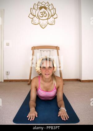 Junge hübsche Frau ist Yoga in ihrem rosa sport Anzug mit einem Feng Gong im Hintergrund. Stockfoto