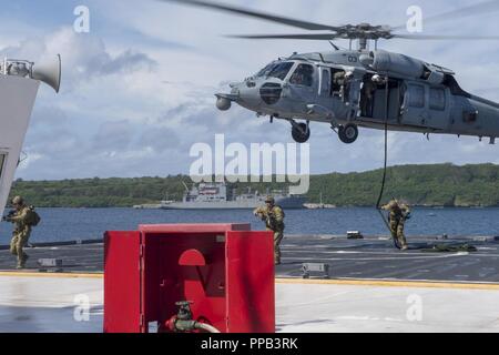 Segler für die Beseitigung von Explosivstoffen Mobile Einheit (EODMU) 5, Hubschrauber Meer Combat Squadron 25 und Australische Soldaten verhalten besuchen, Board, Durchsuchung und Beschlagnahme Operationen an Bord der maritimen Vorpositionierung ship USNS 1st Lieutenant Jack Lummus (T-AK 3011) während der Ausbildung "Pyrocrab' bei Apra Harbor, Guam, 15 August, 2018. Pyrocrab ist eine Biennale Ebene der Ausbildung, die auf die Stärkung der Beziehungen und die Verbesserung der Interoperabilität zwischen der U.S. Navy und der australischen Streitkräfte konzentriert. EODMU-5 ist zum Kommandanten, Task Force 75, die primäre Expeditionary task force Speichereinbauort zugeordnet Stockfoto