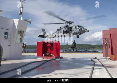 Segler für die Beseitigung von Explosivstoffen Mobile Einheit (EODMU) 5, Hubschrauber Meer Combat Squadron 25 und Australische Soldaten verhalten besuchen, Board, Durchsuchung und Beschlagnahme Operationen an Bord der maritimen Vorpositionierung ship USNS 1st Lieutenant Jack Lummus (T-AK 3011) während der Ausbildung "Pyrocrab' bei Apra Harbor, Guam, 15 August, 2018. Pyrocrab ist eine Biennale Ebene der Ausbildung, die auf die Stärkung der Beziehungen und die Verbesserung der Interoperabilität zwischen der U.S. Navy und der australischen Streitkräfte konzentriert. EODMU-5 ist zum Kommandanten, Task Force 75, die primäre Expeditionary task force Speichereinbauort zugeordnet Stockfoto