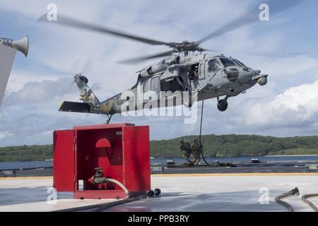Segler für die Beseitigung von Explosivstoffen Mobile Einheit (EODMU) 5, Hubschrauber Meer Combat Squadron 25 und Australische Soldaten verhalten besuchen, Board, Durchsuchung und Beschlagnahme Operationen an Bord der maritimen Vorpositionierung ship USNS 1st Lieutenant Jack Lummus (T-AK 3011) während der Ausbildung "Pyrocrab' bei Apra Harbor, Guam, 15 August, 2018. Pyrocrab ist eine Biennale Ebene der Ausbildung, die auf die Stärkung der Beziehungen und die Verbesserung der Interoperabilität zwischen der U.S. Navy und der australischen Streitkräfte konzentriert. EODMU-5 ist zum Kommandanten, Task Force 75, die primäre Expeditionary task force Speichereinbauort zugeordnet Stockfoto