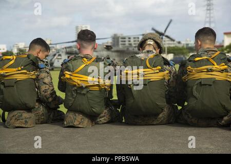 Marines mit Landung Support Unternehmen, 3. Transport Support Battalion, 3. Marine Logistics Group, warten neben dem Camp parade Deck fördern, an Bord ein CH-53E Super Stallion Hubschrauber während Fallschirm- und Luftzufuhr Training Operations Aug 14, 2018 at Ie Shima, Okinawa, Japan. Das Training bestand aus Low-level-statische Linie und militärischen freien Fall springt auf 10.000 Fuß um die Marines beherrschen als Fallschirm rigger und der Spezialisten zu halten. Stockfoto