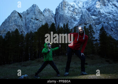 Kind zeigt seine Karate bewegt sich zu seiner Mutter, und sie tragen die Scheinwerfer auf Gras bedeckte Wiese mit hohen Bergen im Hintergrund, die Julischen Alpen, Slowenien Stockfoto